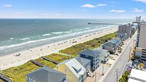 A coastal residential area with a beach, a pier, and a row of houses with balconies.