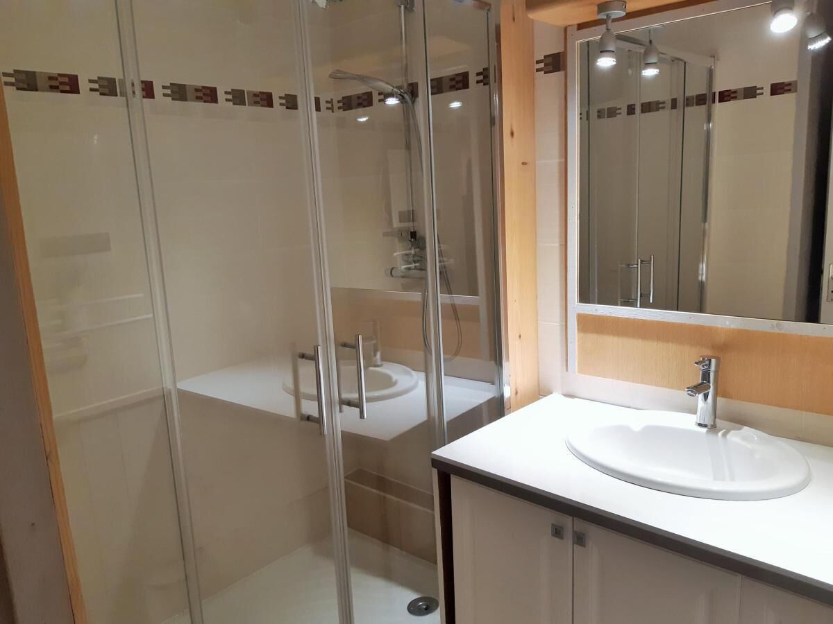 A bathroom with a glass-enclosed shower, a white sink, and a mirror above the sink.