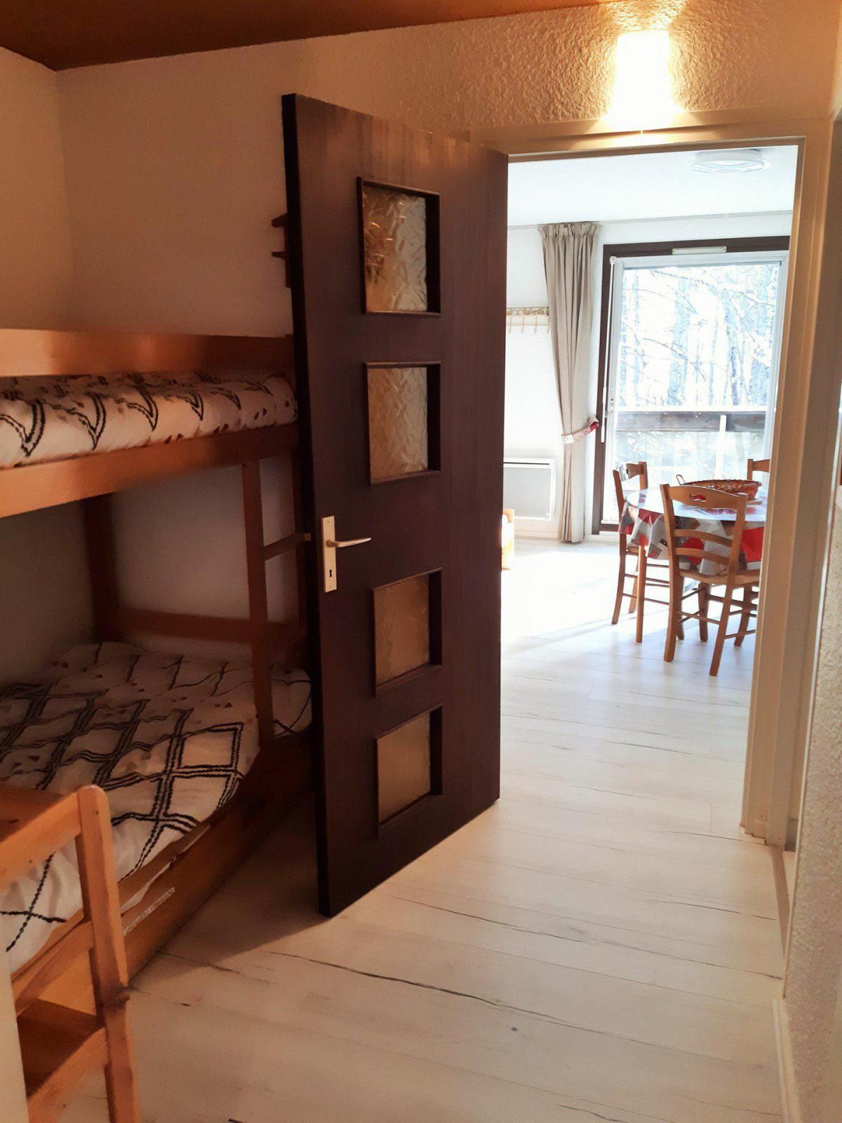 A room with a bunk bed, a door with a window, and a dining area with chairs and a table.