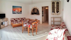 Ein gemütliches Wohnzimmer mit einer Couch, einem Esstisch und einem Fernseher.
