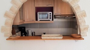 Eine Küche mit einem Steingewölbe, einer Mikrowelle, Holzschränken, einer Kaffeemaschine und einem Holztisch.