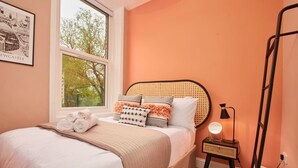 A neatly made bed with rolled towels, a bedside lamp, and a framed picture on the wall. - Scandi Chique Newcastle Abode (Newcastle upon Tyne)