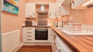 A modern kitchen with white cabinets, a stainless steel range hood, a built-in oven, a microwave, and a wooden countertop. - Scandi Chique Newcastle Abode (Newcastle upon Tyne)