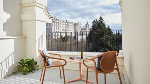 Un balcon avec deux fauteuils en osier, une petite table ronde et un pot de fleurs.