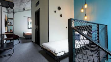 A modern room with a bunk bed, a desk, a chair, and a small window.