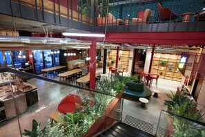 Un espacio interior de varios niveles con zonas de estar, mesas y plantas en macetas.