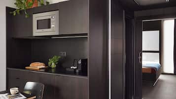 Cocina compacta con microondas, hogaza de pan, cafetera y una pequeña planta.