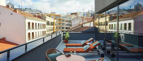 Una terraza en la azotea con sillones de descanso, una mesa y una planta en maceta.
