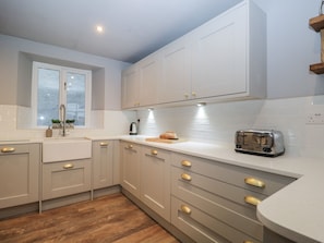 Une cuisine moderne avec des meubles blancs, un plan de travail en bois, un grille-pain et une fenêtre à vitrage dépoli.