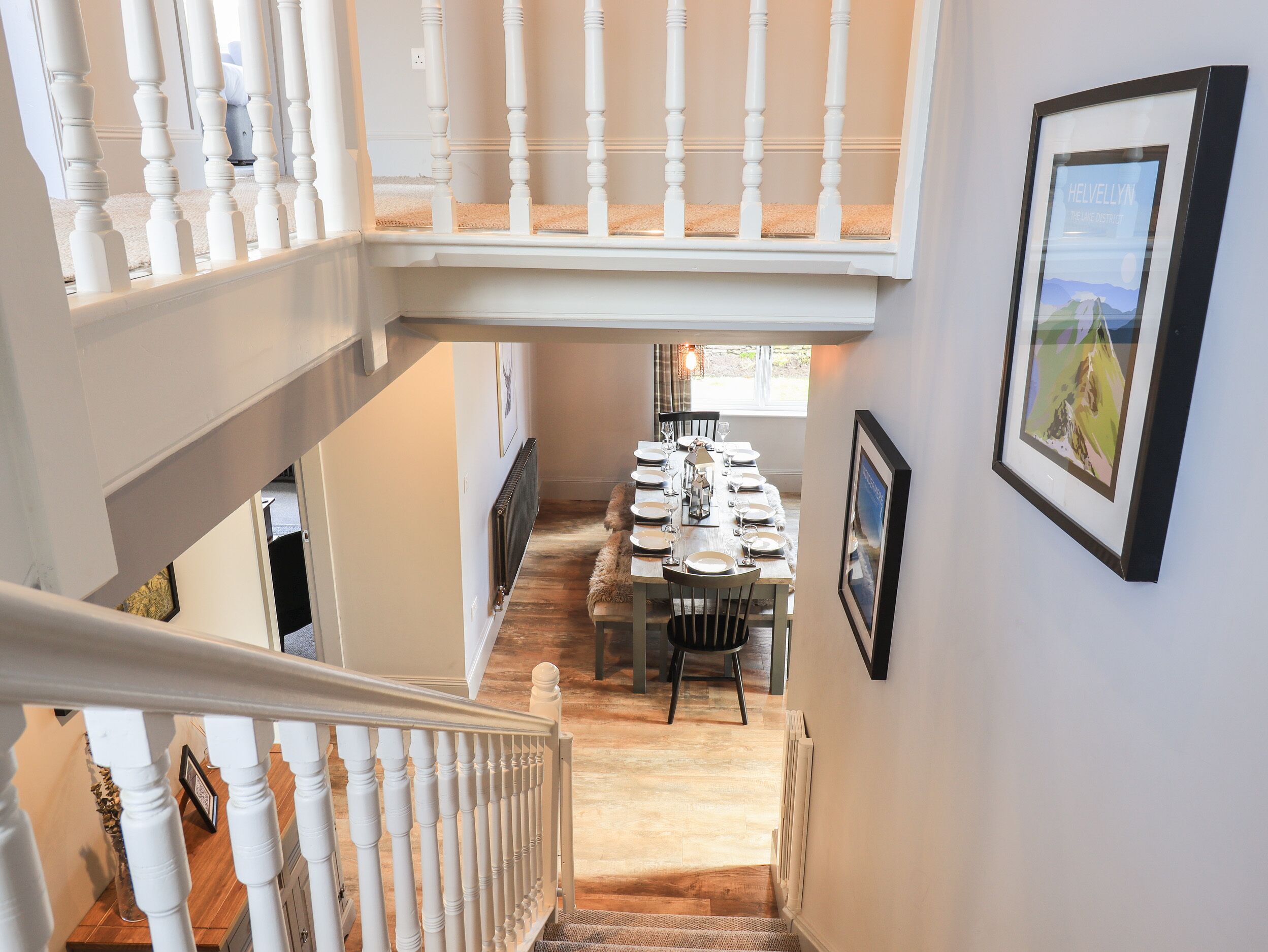 Una escalera conduce a un comedor con techo alto y vistas al exterior.