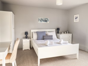 Une chambre bien rangée, avec un lit, des tables de chevet, un bureau et une chaise.