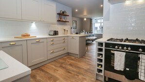Une cuisine moderne avec des meubles blancs, une cuisinière encastrée et un plancher en bois.