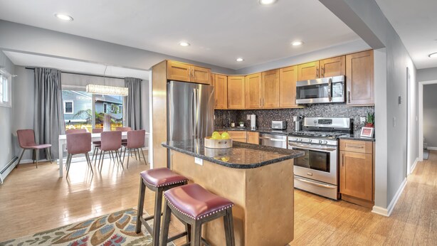 Una cocina moderna con armarios de madera, electrodomésticos de acero inoxidable y una isla central con taburetes.