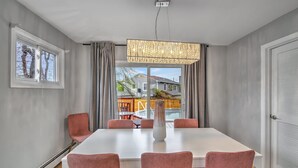 Un comedor moderno con una mesa blanca, sillas rosadas y un jarrón alto.