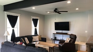 A modern living room with a sofa, armchair, coffee table, and a TV mounted on the wall.