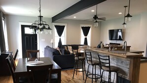 A modern kitchen with a bar area, wooden flooring, and a dining area with a table and chairs.