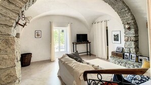Una habitación acogedora con un arco de piedra, una cama, un televisor y cuadros en la pared.