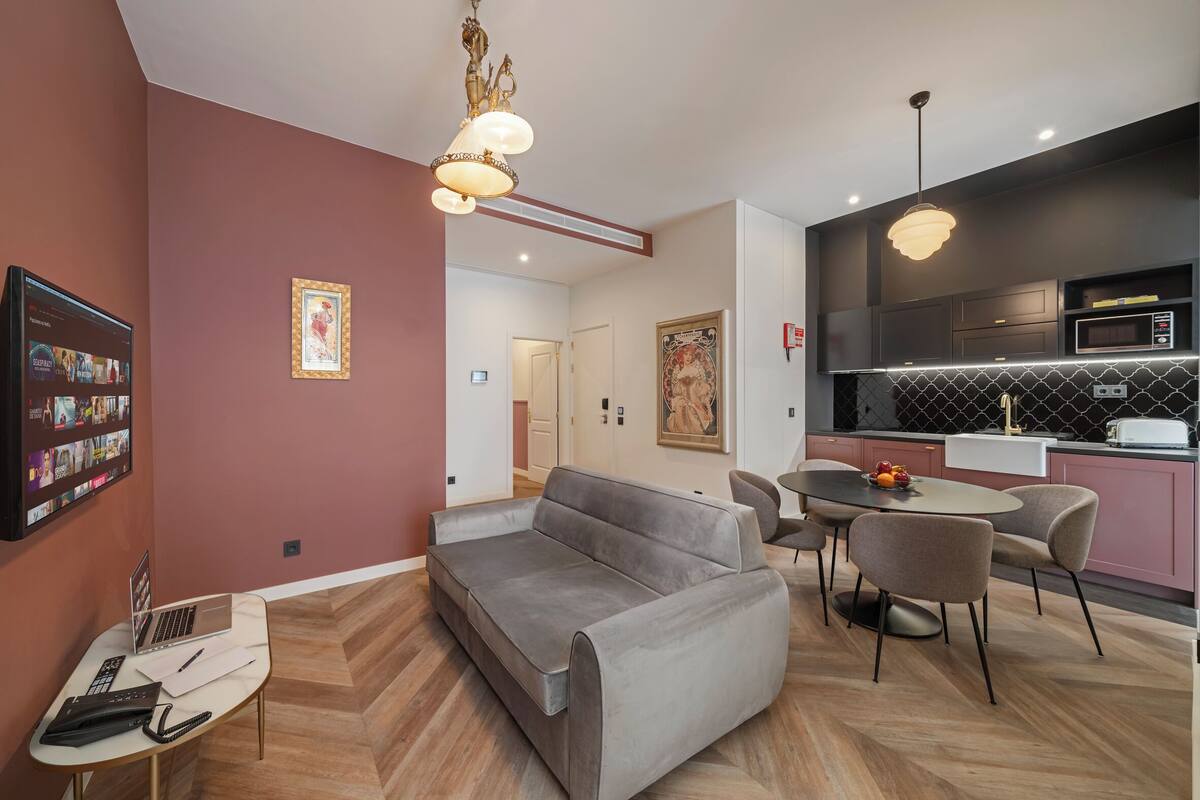 Uma sala de estar moderna com um sofá cinzento, uma mesinha e uma área de refeições com cadeiras.