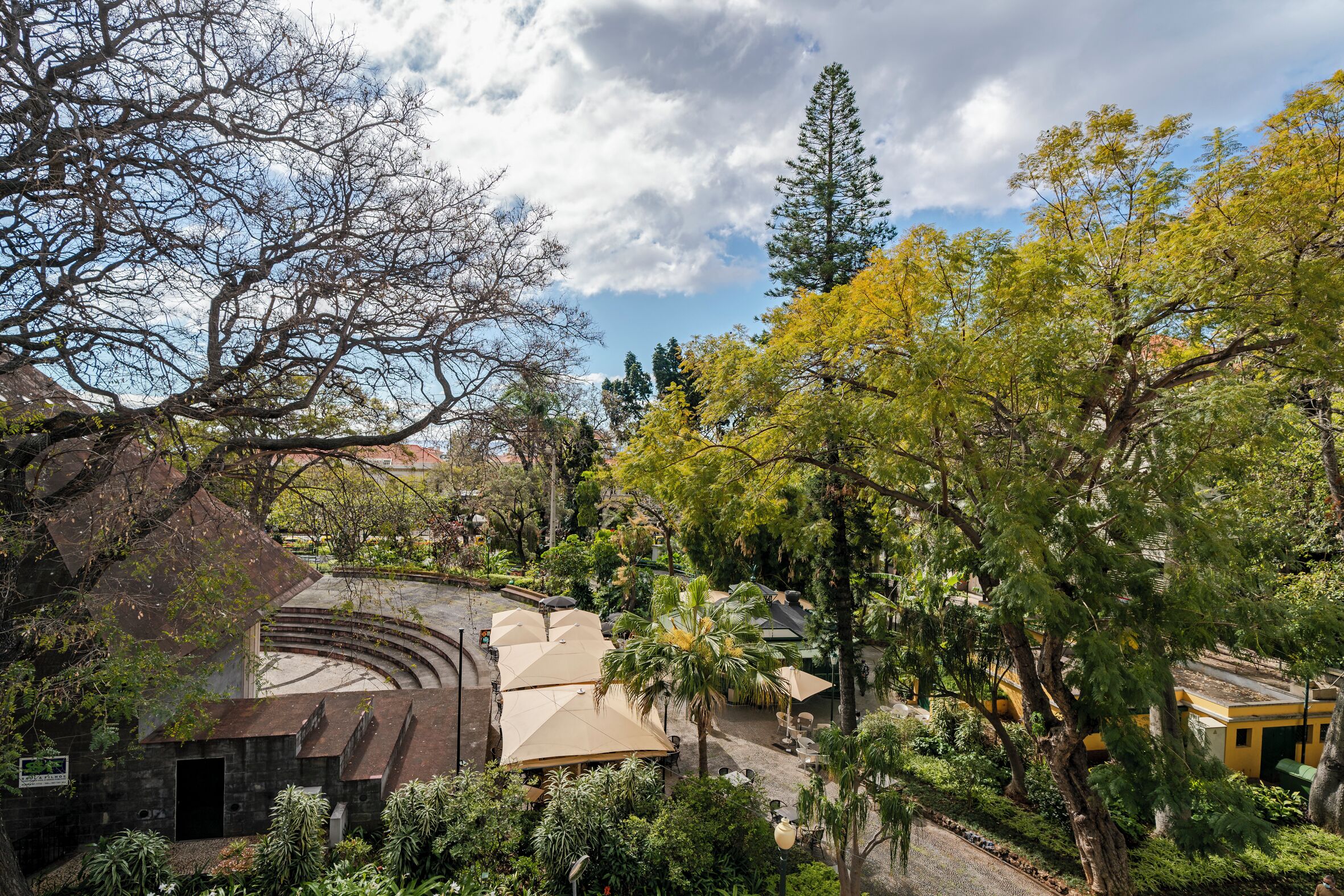 Un patio con un escenario, zonas de estar y árboles.