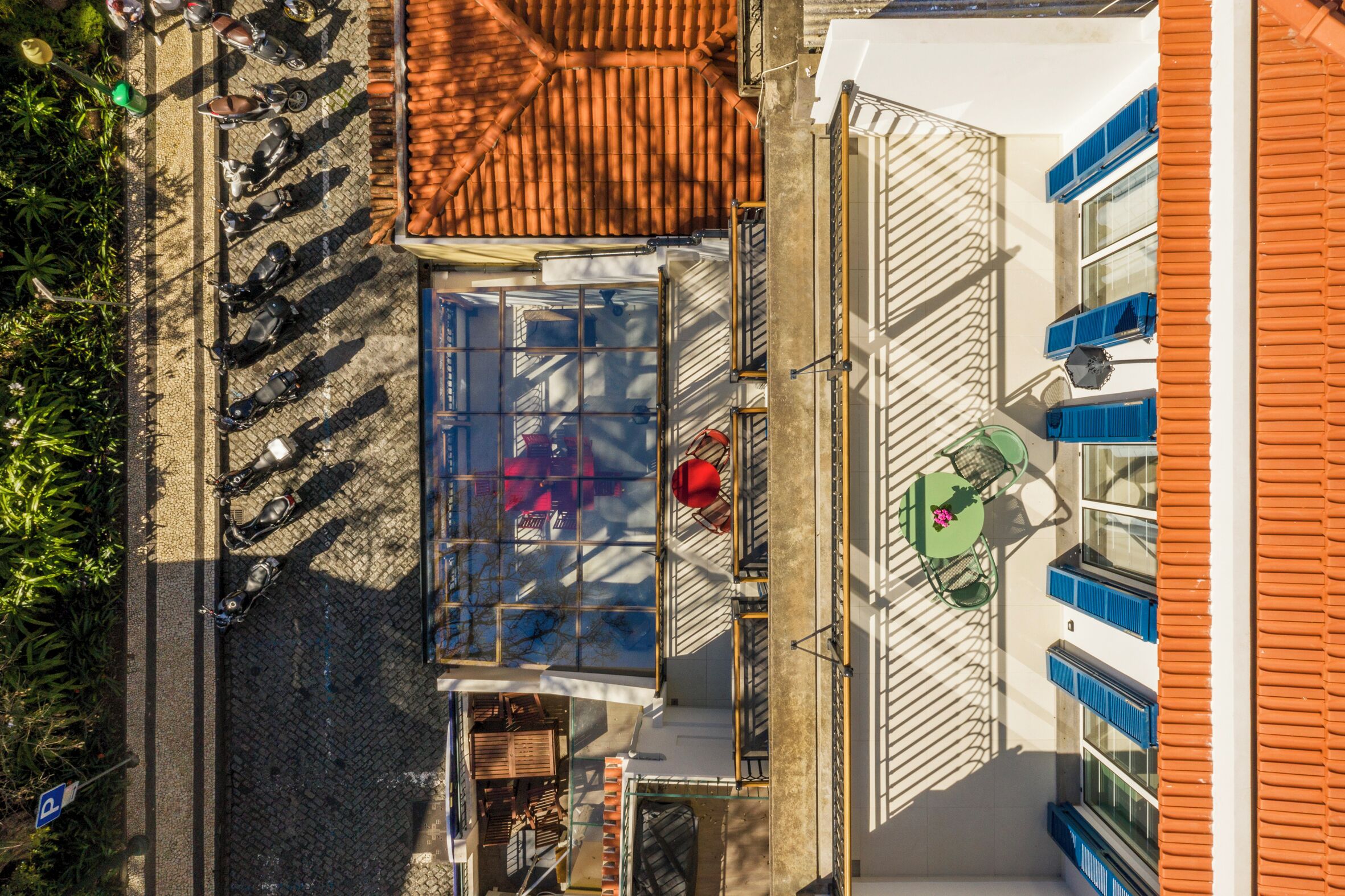 Eine Vogelperspektive eines Gebäudes mit einem Ziegeldach, einem Glasbalkon und einem kleinen Tisch mit Stühlen.