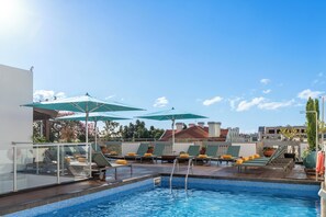 Alberca al aire libre, sombrillas en la alberca y camastros 