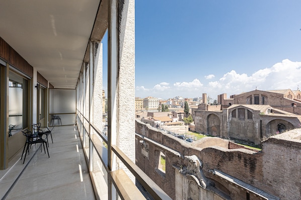 Un balcon offrant une vue sur des bâtiments historiques et un ciel dégagé.