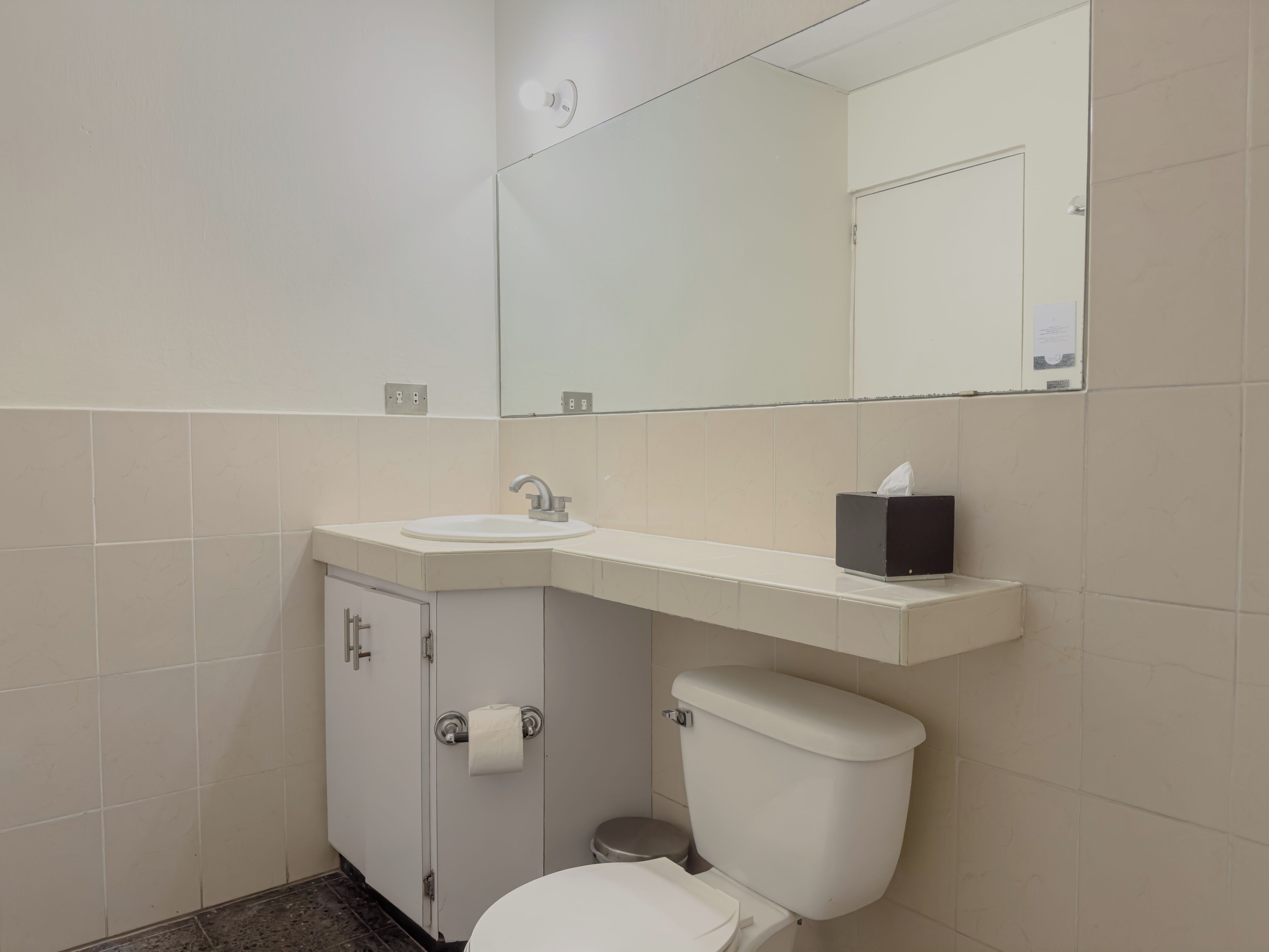 Un baño con lavabo blanco, espejo, inodoro y armario.