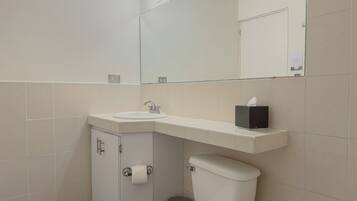 Un baño con lavabo blanco, espejo, inodoro y armario.