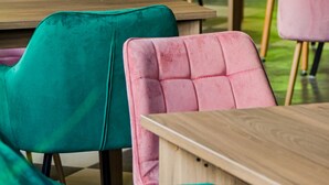 A seating area with teal and pink upholstered chairs and wooden tables.