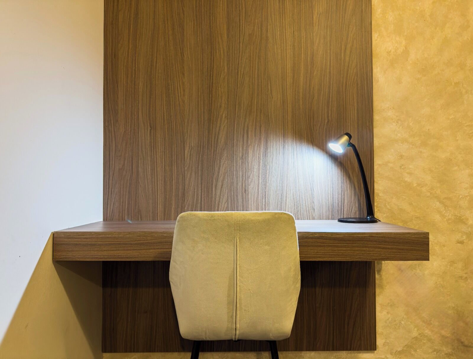 A wooden desk with a lamp and a chair.