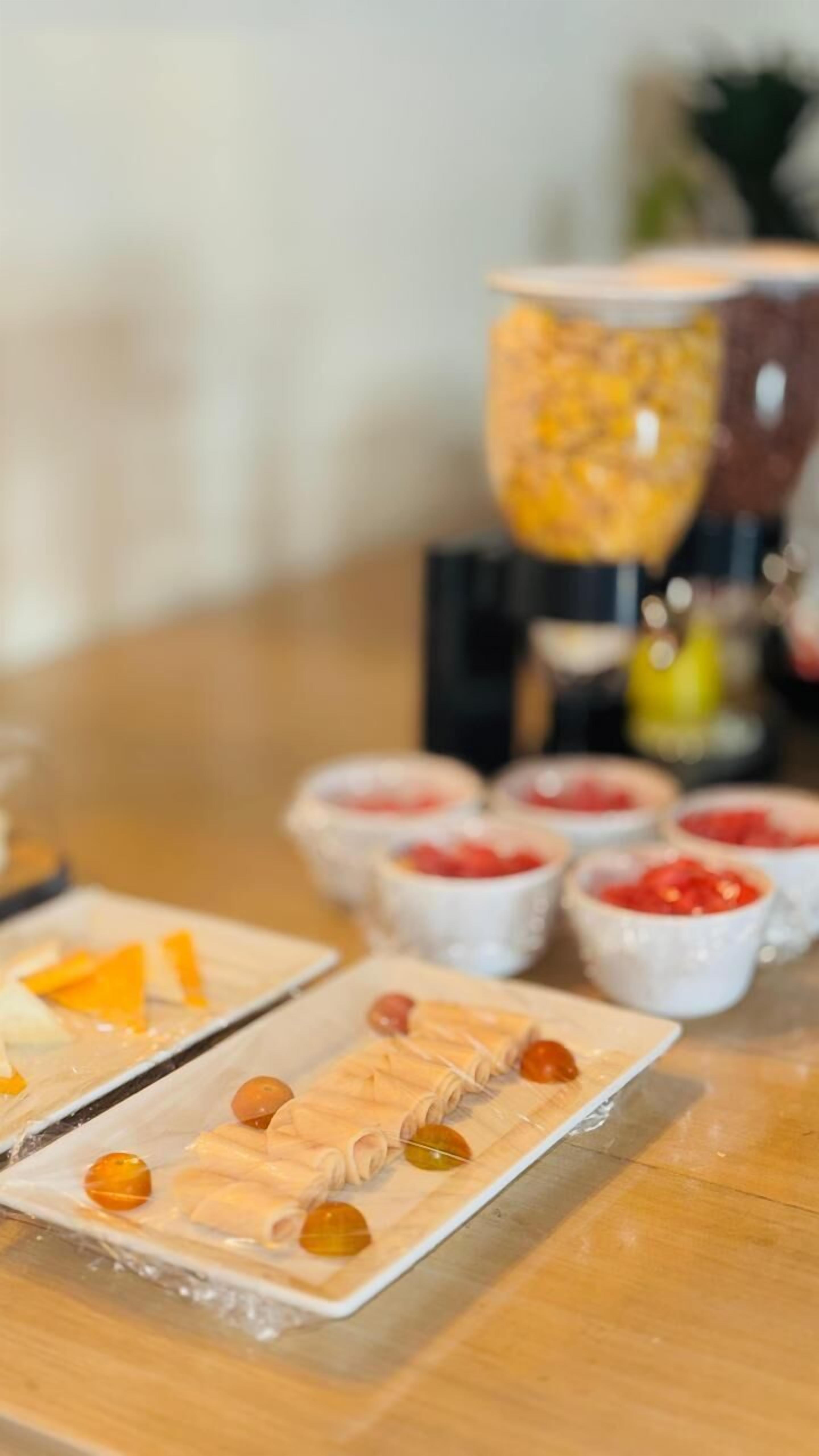 A table with various food items, including a dish with rolled pastry and orange slices, and small bowls with red and yellow contents.