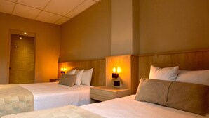 A hotel room with two beds, a large bed in the foreground, and a shower area.