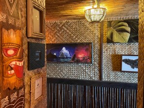 Pared con diseños tejidos, obras de arte enmarcadas y una lámpara colgante.