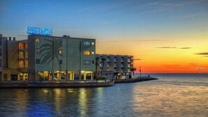 A waterfront hotel with a prominent 'SAILPORT' sign, featuring multiple floors and a dock extending into the water. - Tiki Themed Condo on Tampa Bay (Tampa)