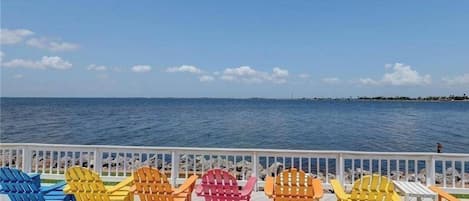Eine Terrasse mit bunten Adirondack-Stühlen, die auf ein Gewässer ausgerichtet sind.