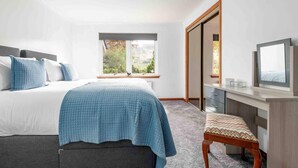 A bedroom with a bed, a desk, a chair, and a television. - 3 Bedroom Bungalow With Htub & Private Loch Access (Crieff)