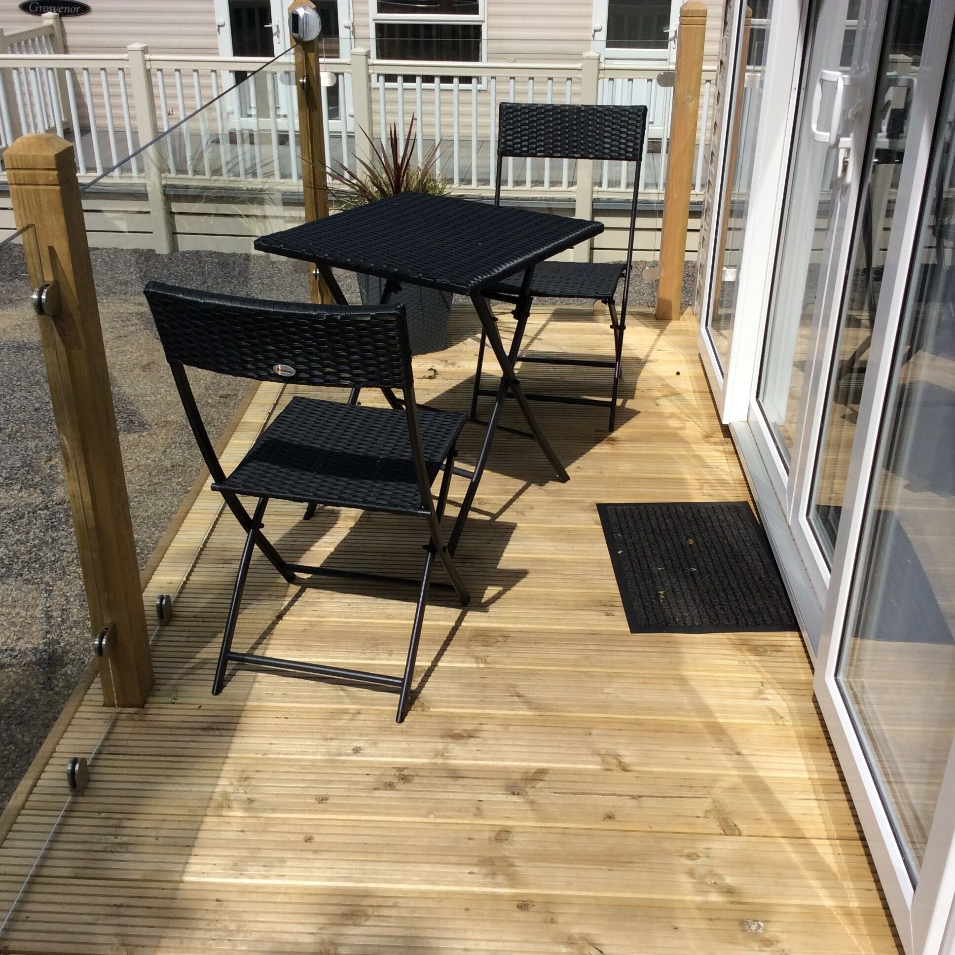 Una terraza de madera con dos mesas y sillas de metal negro.