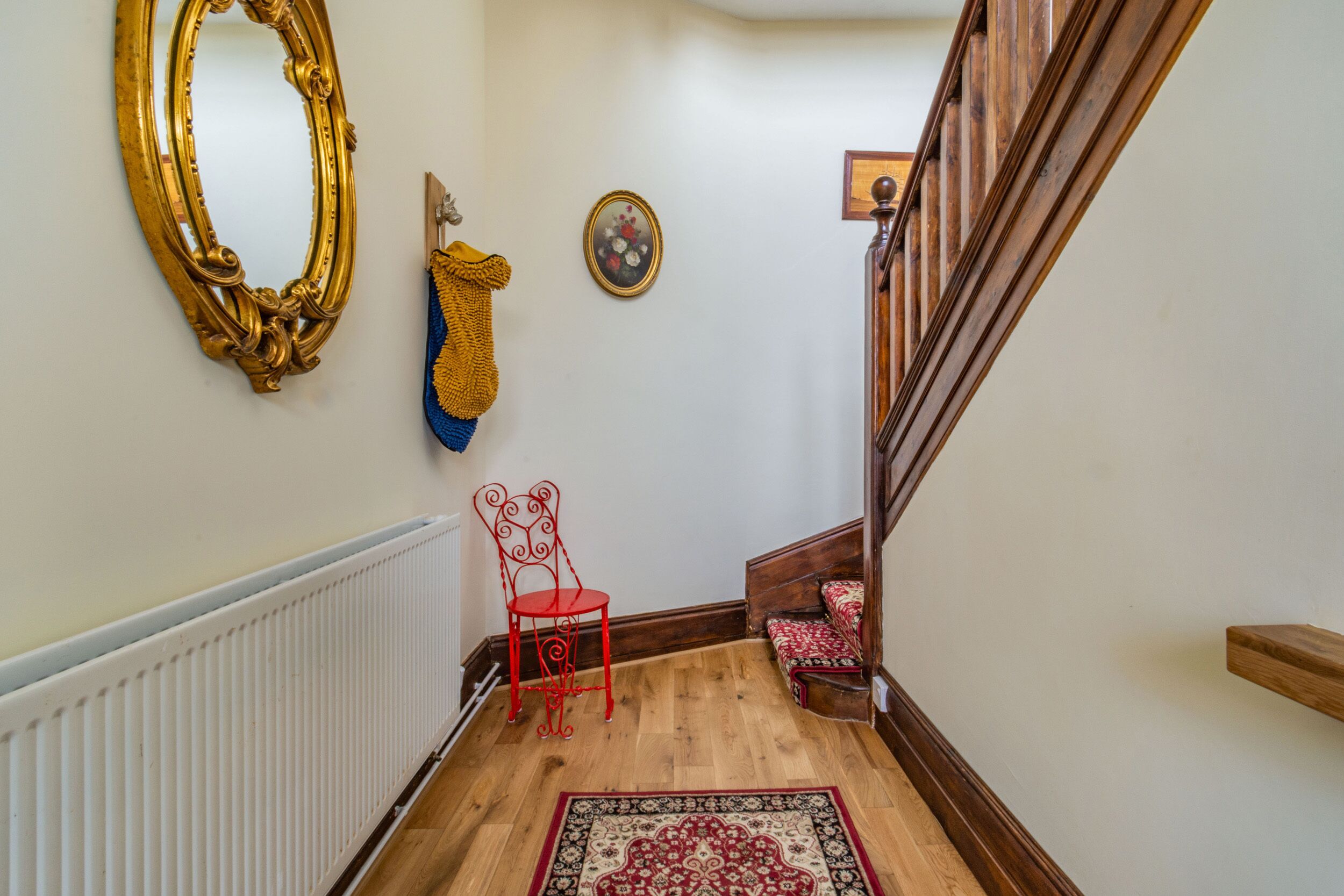 A wooden staircase with a red chair and a patterned rug.
