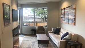 A living room with a sofa, coffee table, and a TV mounted on the wall. - Luxury Condo - Easy Walk to Downtown, Ocean & Attractions (Victoria)
