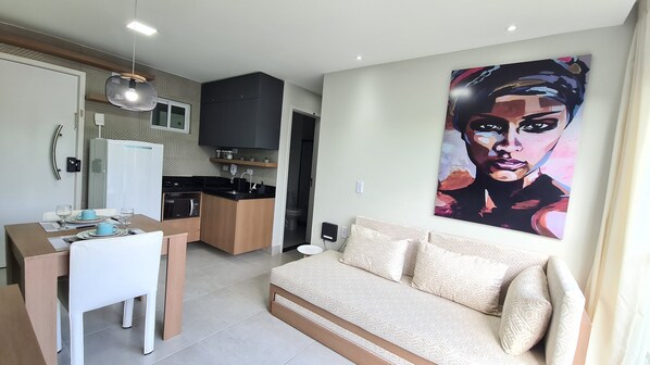 A compact living space with a kitchenette, a dining area, and a sofa. - Na Praia Flats Centro AD (Ipojuca)