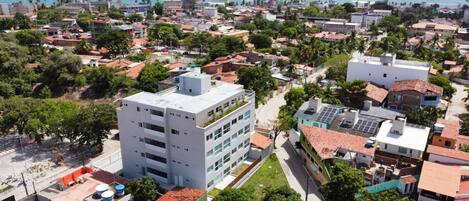 A multi-story building with a flat roof, surrounded by residential buildings and palm trees.