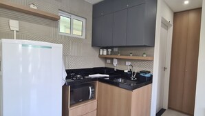 Een kleine keuken met een koelkast, fornuis, magnetron en een gootsteen.