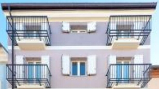 Un immeuble à plusieurs étages doté de balcons, d’une entrée centrale et d’une porte bleue.