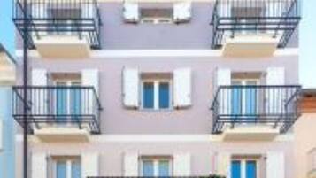 Un edificio a più piani con balconi, un ingresso centrale e una porta blu.