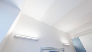 Ein Zimmer mit weißen Wänden, einem gerahmten Kunstwerk und Einbaustrahlern.