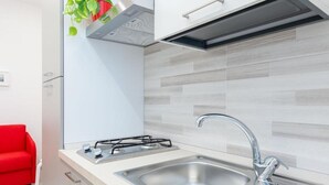 Une cuisine moderne équipée d’une cuisinière à gaz, d’un évier en acier inoxydable et d’une chaise rouge.