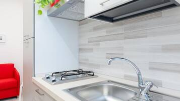 Una cucina moderna con piano cottura a gas, lavello in acciaio inossidabile e una sedia rossa.