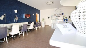 A modern hotel lobby with a blue accent wall, a reception desk, and a seating area with white and purple chairs. - Hotel Noto Marina a Mare Spa (Noto)