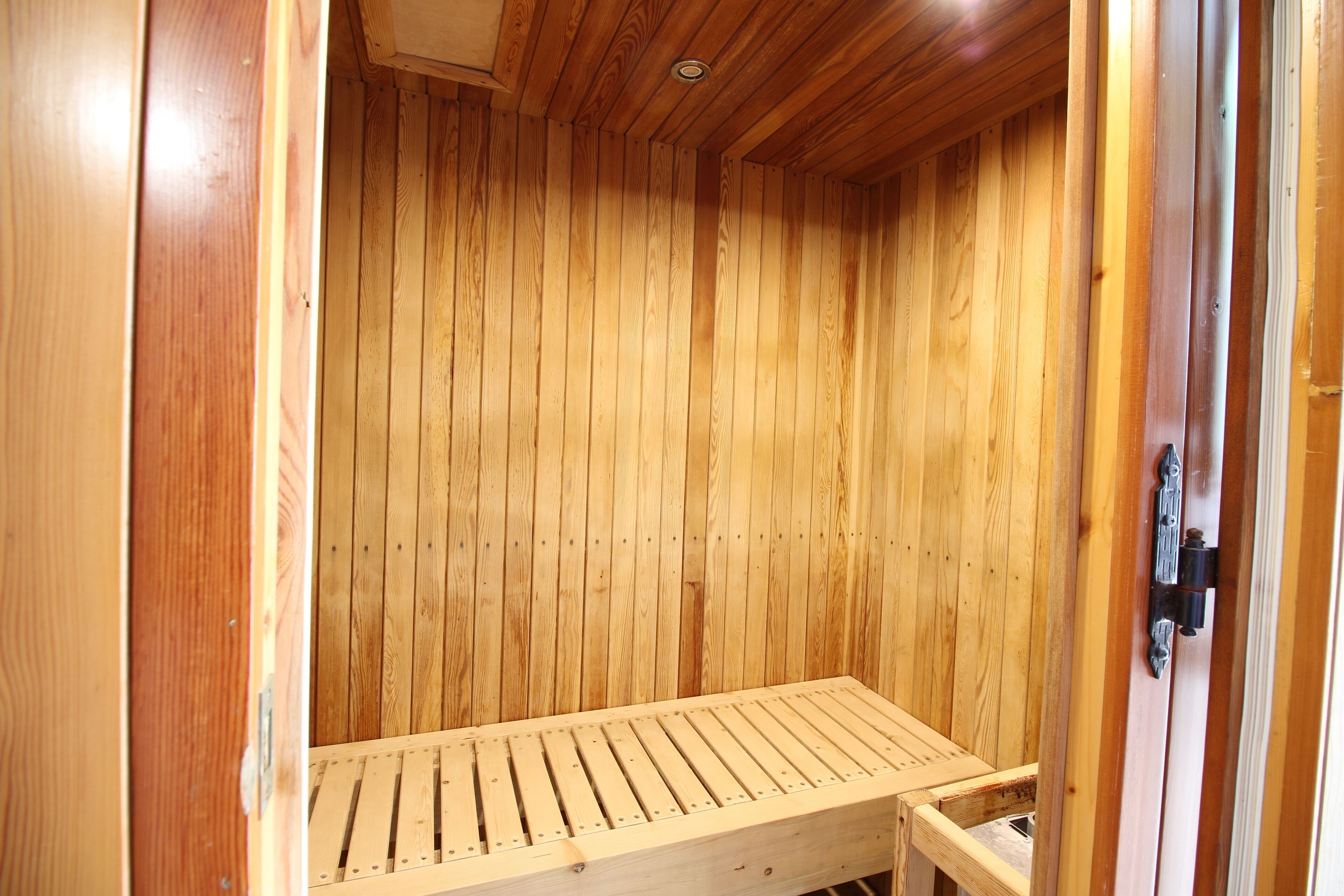 A wooden sauna with a bench and a door.