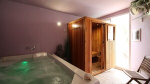 A spa room with a large bathtub, wooden sauna, and a chair. - Hotel Noto Marina a Mare Spa (Noto)